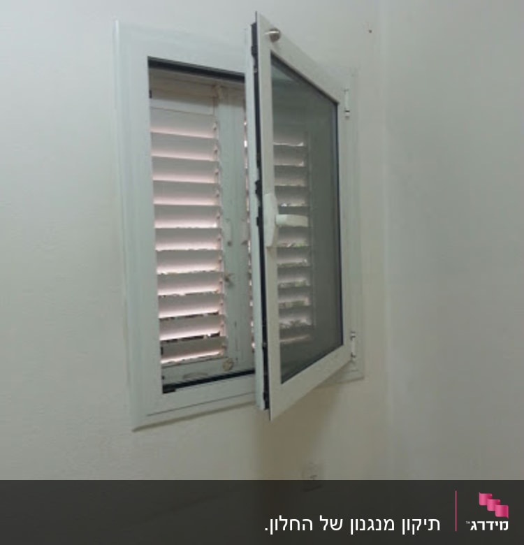 חלון עם תריסים פתוחים למחצה על קיר לבן